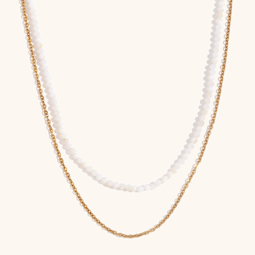 White beaded necklace with gold chain, delicate double layer jewelry on beige background