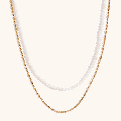 White beaded necklace with gold chain, delicate double layer jewelry on beige background