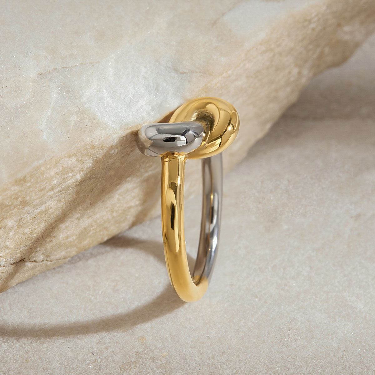 Knot ring placed beside matching earrings in lifestyle flatlay