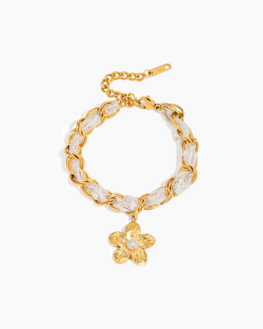 Gold bracelet with a floral charm on a white background