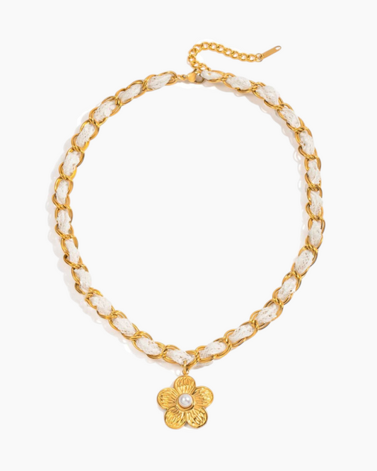 Gold chain necklace with white beads and a floral pendant on a white background