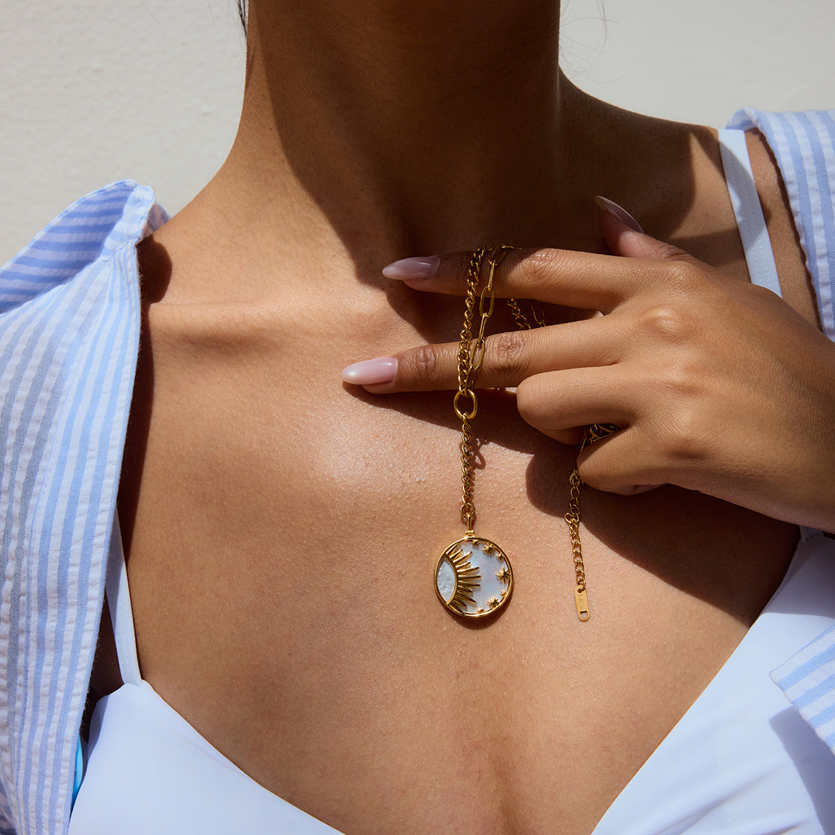 Close-up of gold drop necklace with celestial pendant on model’s chest