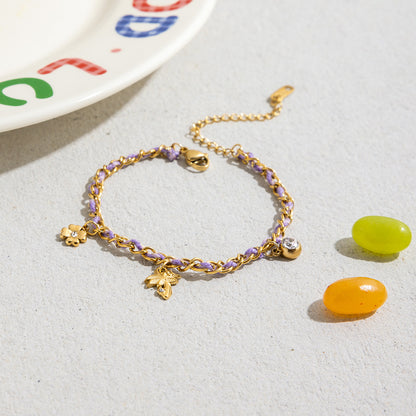 Golden tropical-themed bracelet with palm and flower charms styled with layered accessories in sunshine