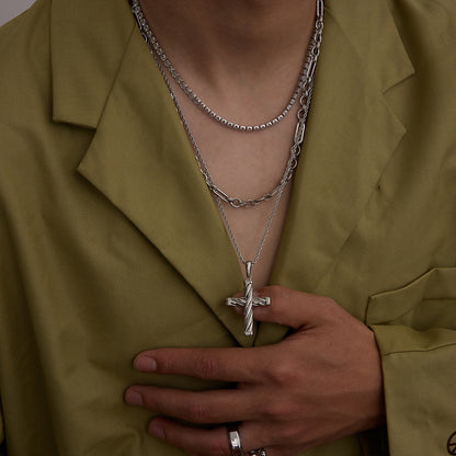 Model wearing layered silver chain necklaces with cross pendant and open shirt
