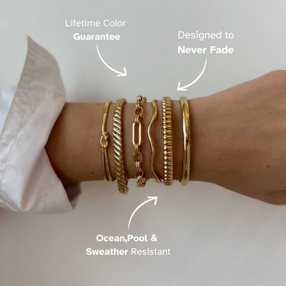 Stacked gold bangles including beaded cuff, worn by model in cream dress