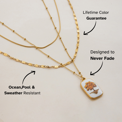 Flat lay of gold layered necklace with tree pendant and colorful stones on textured background