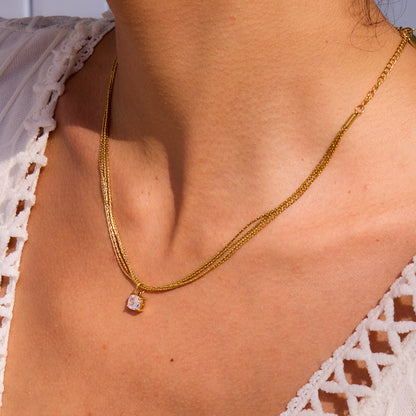 Model layering gold chain necklaces, featuring solitaire zircon pendant for summer look