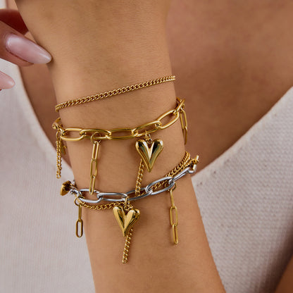 Close-up of layered heart bracelet styled with neutral knitwear