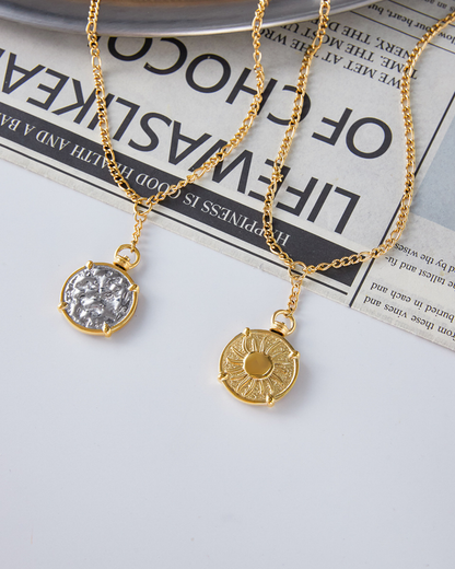 Two gold necklaces with pendants on a newspaper background