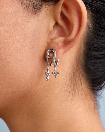 Side profile view of woman wearing layered silver hoop earrings with charms