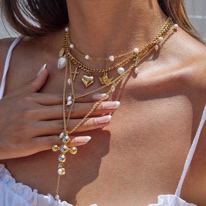 Layered jewelry look featuring pearl and gold cross bracelet