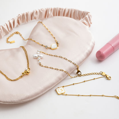 Gold necklaces on a pink jewelry pouch with a pink pen next to it.