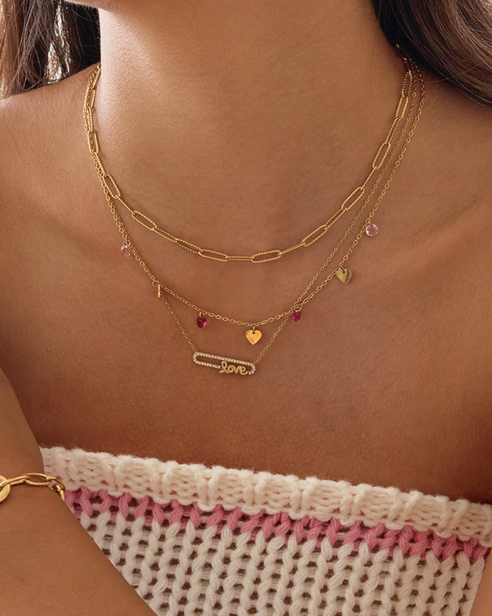 Close-up of a model’s neckline wearing multiple gold necklaces with the LOVE charm necklace as the centerpiece, perfect for everyday layering.