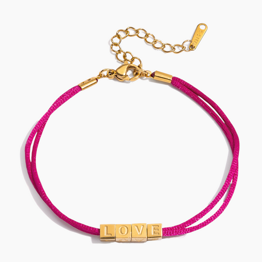 Pink bracelet with gold 'LOVE' charm on a white background