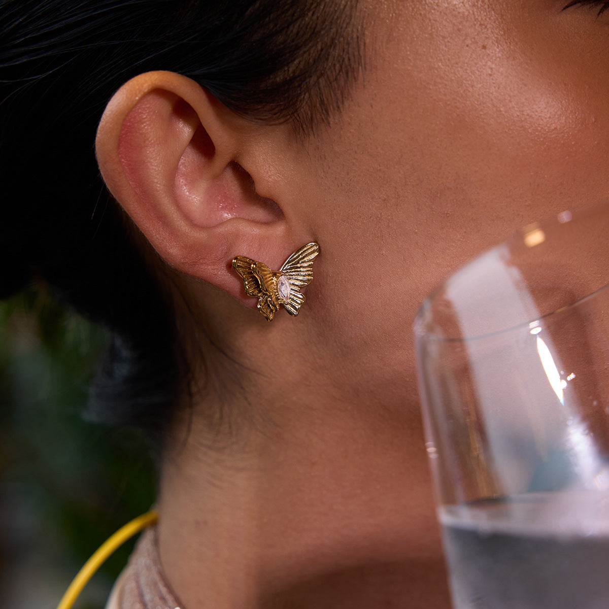 Butterfly earrings with textured wings and clear gemstone center worn in lifestyle shot