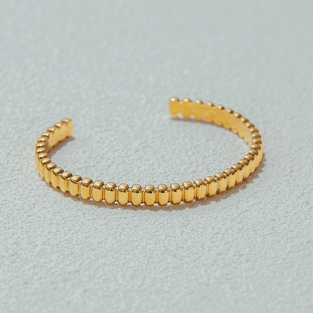Luxury gold cuff bracelet placed on textured stone, elegant photography setup