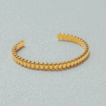 Luxury gold cuff bracelet placed on textured stone, elegant photography setup