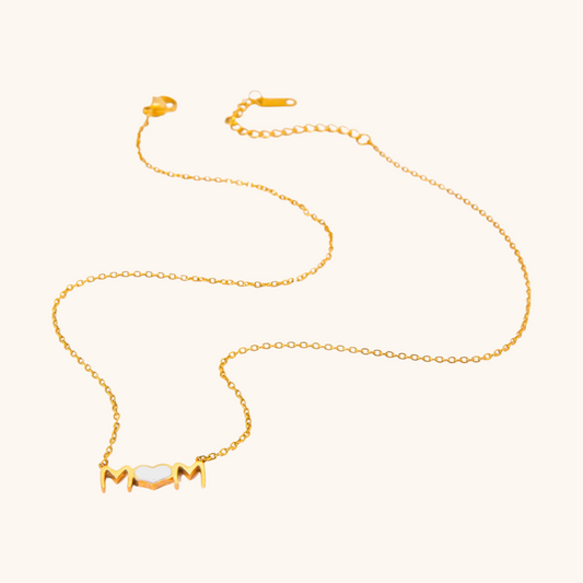 Gold mom heart necklace with white enamel, laid flat on white background