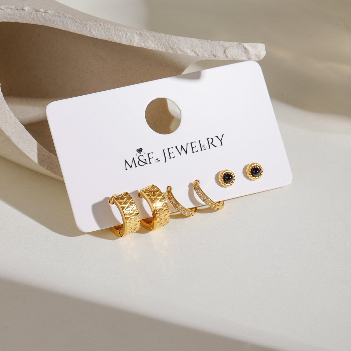 Jewelry card showing all three pairs of earrings (geometric hoops, cz hoops, and black studs) in daylight.