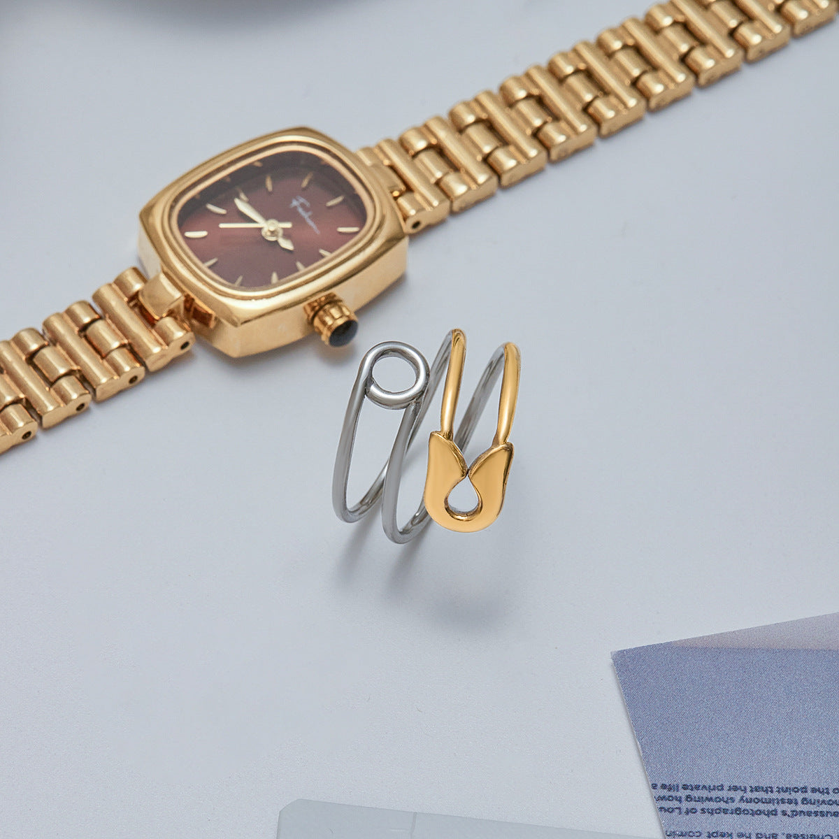 Product-only image of minimalist gold wrap ring with safety pin motif