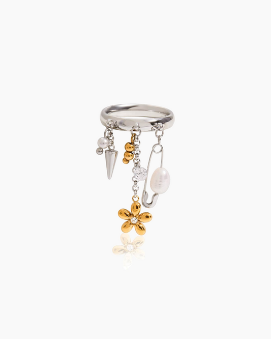 Silver ring with gold and pearl charms on a white background