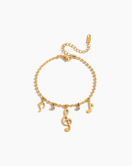 Gold bracelet with musical note charms on a white background