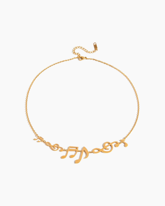 Gold necklace with musical note designs on a white background