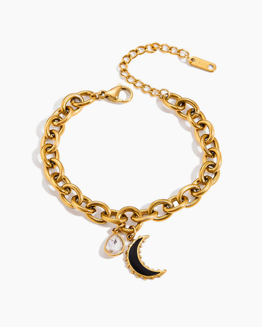 Gold chain bracelet with a moon and star charm on a white background