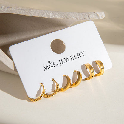 Sleek chunky gold hoop earrings placed on a display card under sunlight