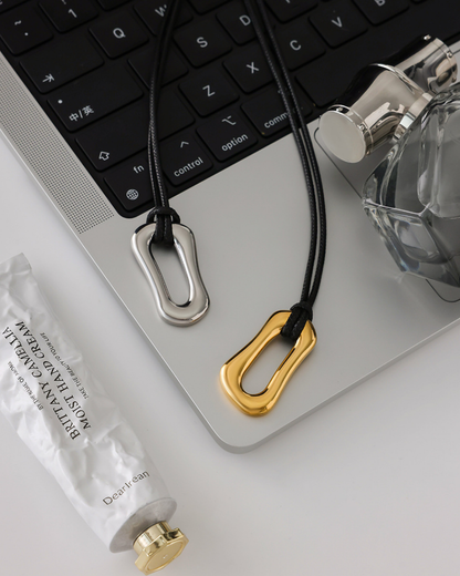 Two keychains, one gold and one silver, on a laptop keyboard with a bottle and tissue paper in the background.