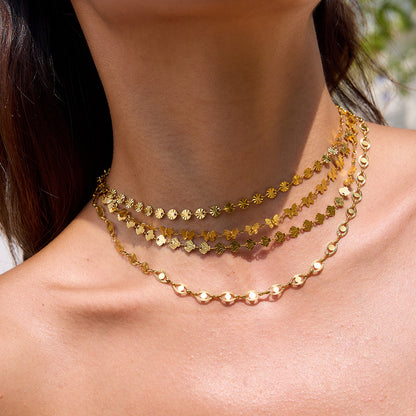 Four gold choker necklaces stacked on model’s neck in outdoor light