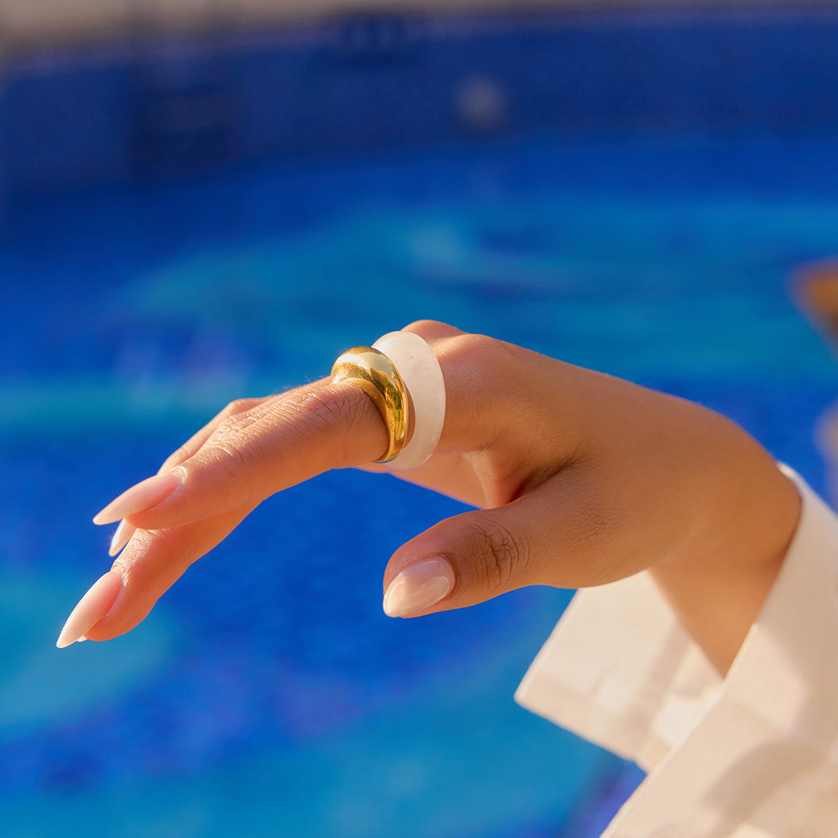 Chunky clear resin ring worn by model by the pool in natural sunlight.