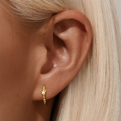 Blonde woman wearing gold butterfly hoop earrings, showing minimalist and lightweight design.