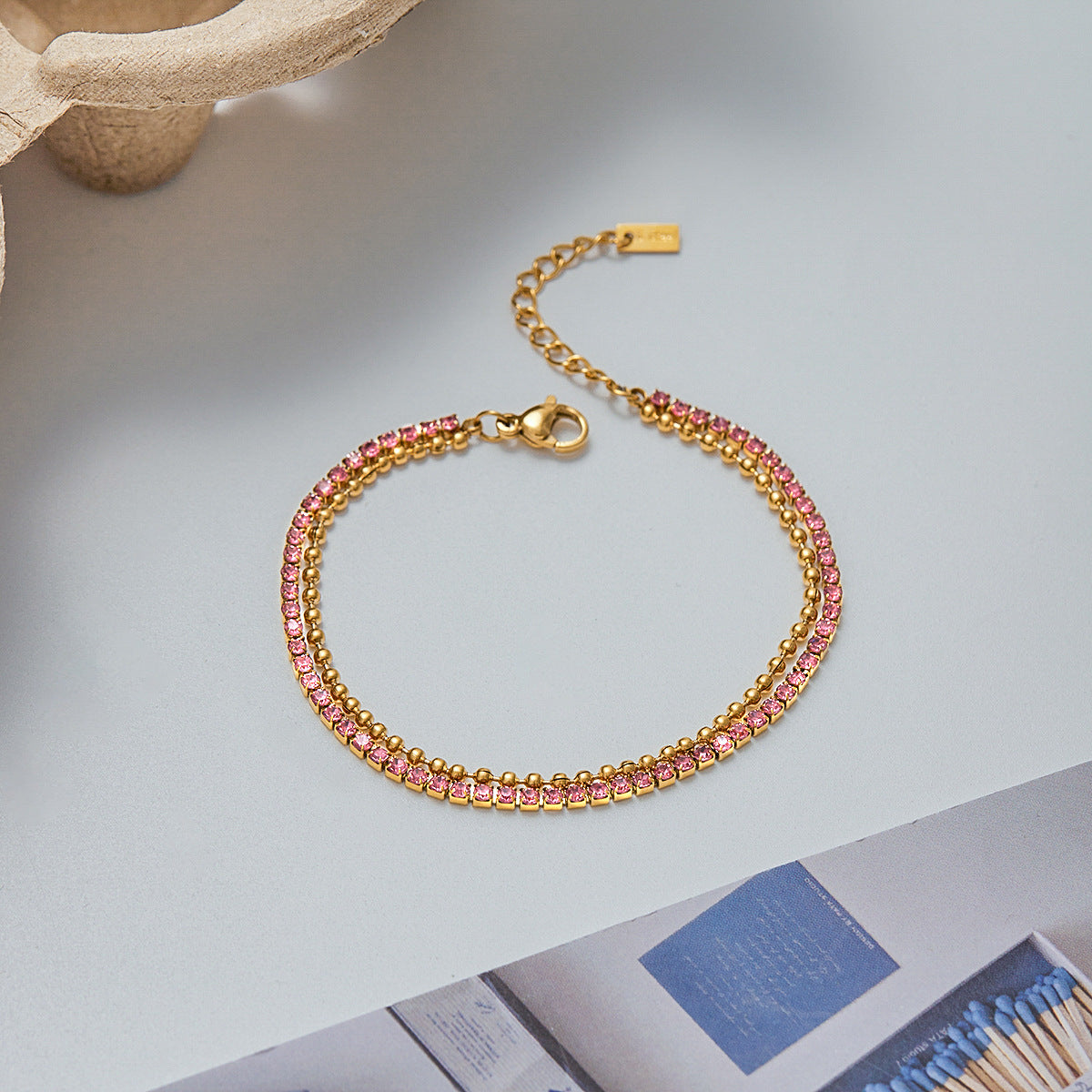 Gold minimalist beaded bracelet with geometric finish laid flat on surface