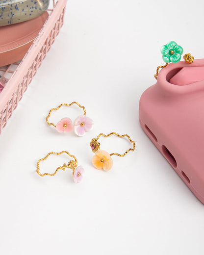 Set of floral phone charms on a pink phone case with a white background