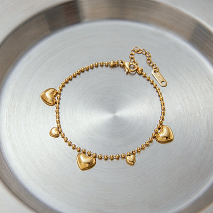 gold bracelet with heart-shaped charms placed on a silver plate