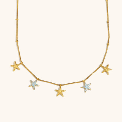 Gold chain necklace with dangling star charms on white background