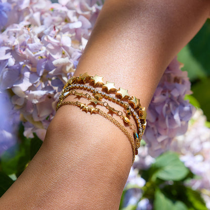 Layered gold star bracelets glowing in natural sunlight