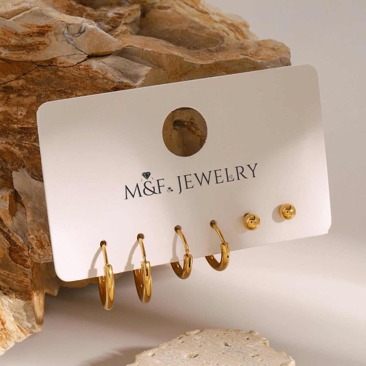 3-pair gold hoop earring set with ball studs on stone slab, close-up detail shot