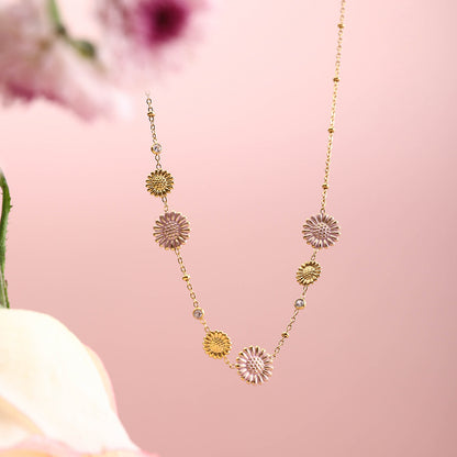 Zoomed-in view of dainty gold necklace with pink and gold daisies