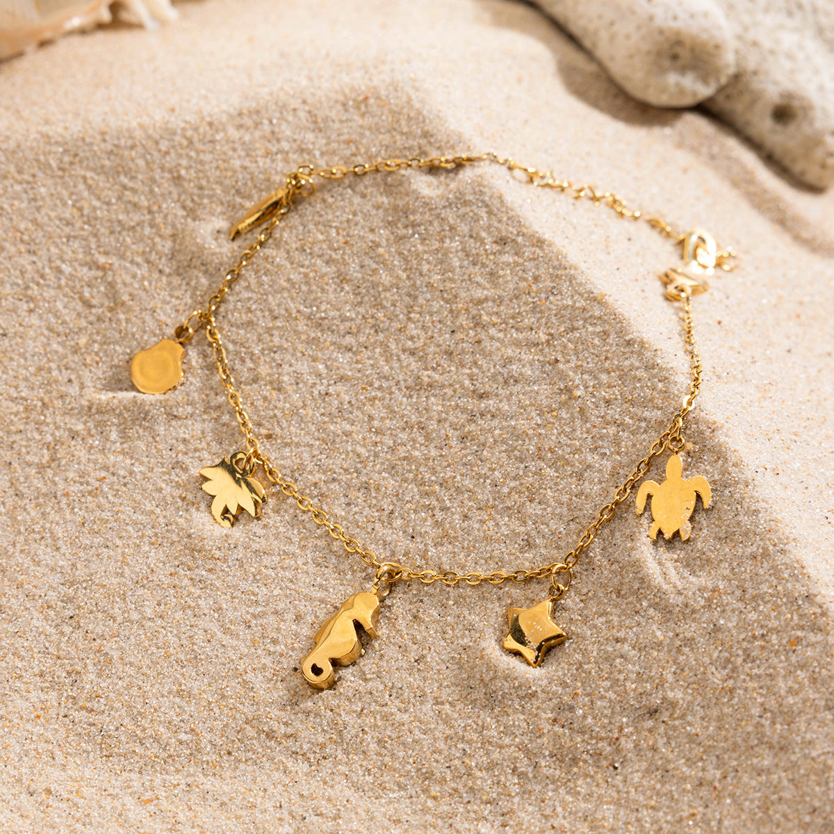 Product-only image of gold bracelet with marine pendants including turtle, fish, and star.