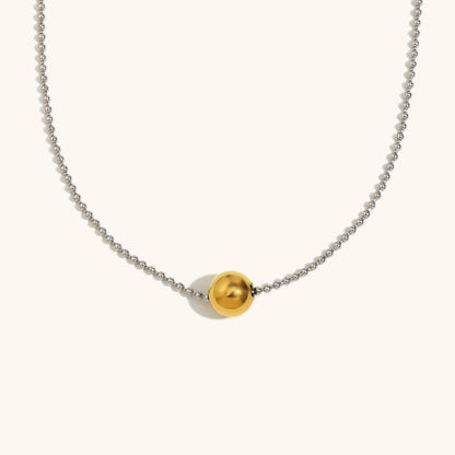 Close-up of gold bead pendant on dainty silver ball chain