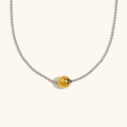 Close-up of gold bead pendant on dainty silver ball chain
