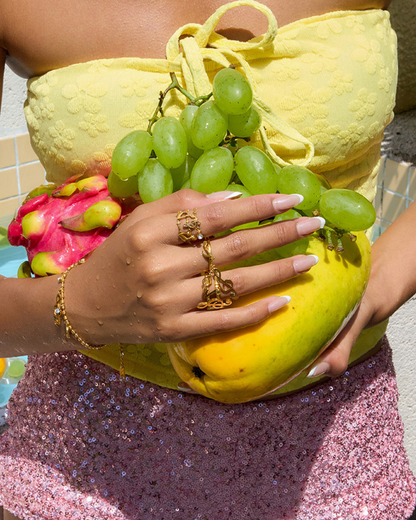 Person holding a bunch of green grapes with a yellow outfit and pink glittery pants.