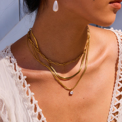 Close-up of woman wearing layered gold necklace with a single clear zircon stone