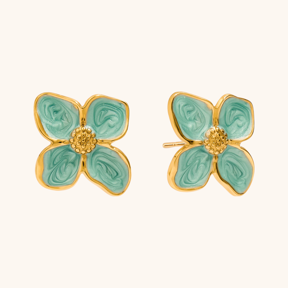 Close-up of floral stud earrings with gold and mint swirl petals
