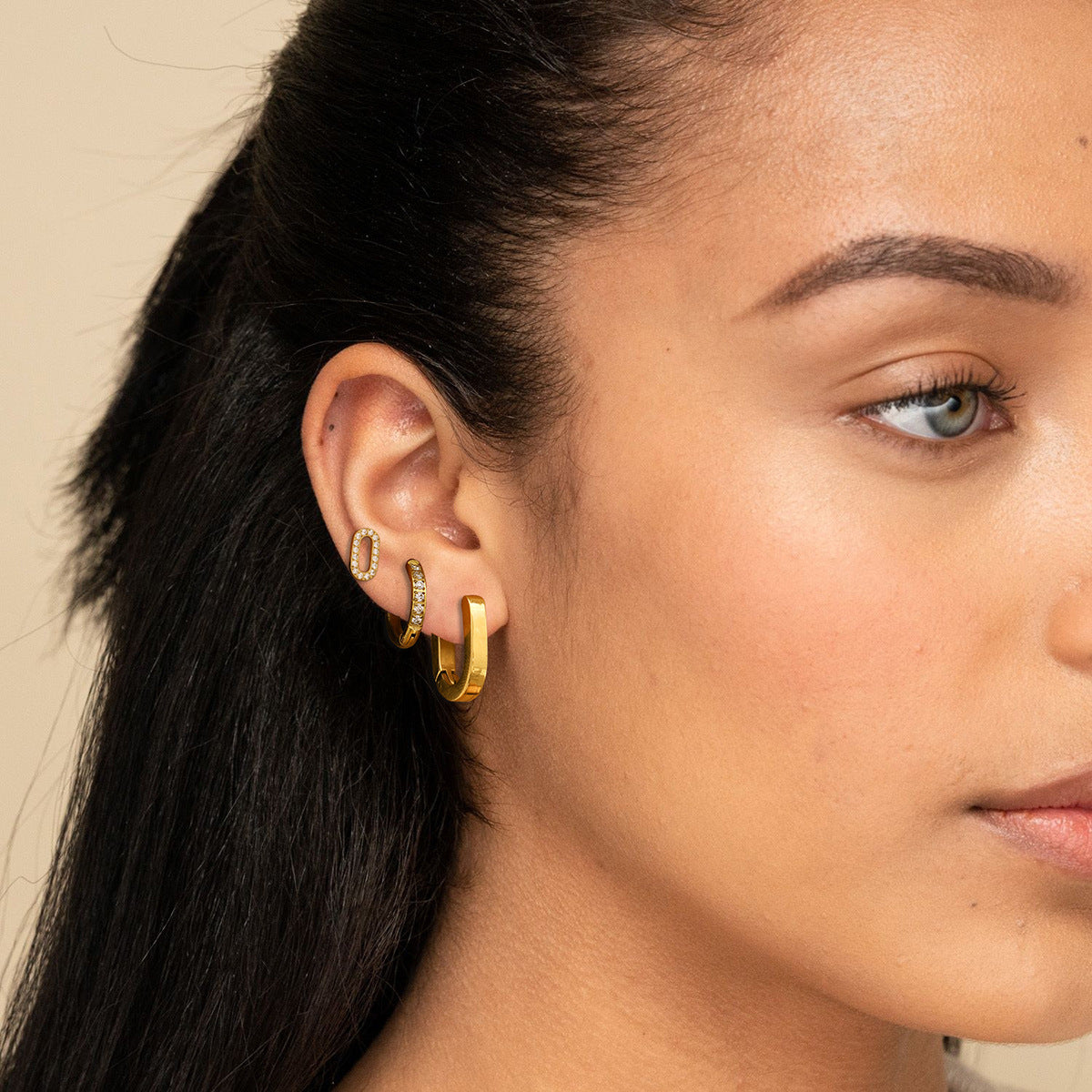 Model wearing gold earring set with layered hoops and pavé studs, perfect for stacking look