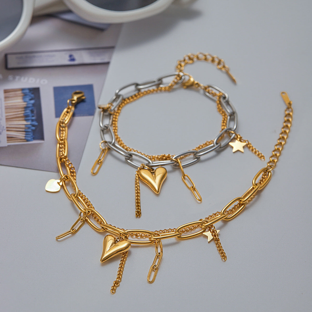 Two-tone chain bracelet with gold heart and star charms on tabletop