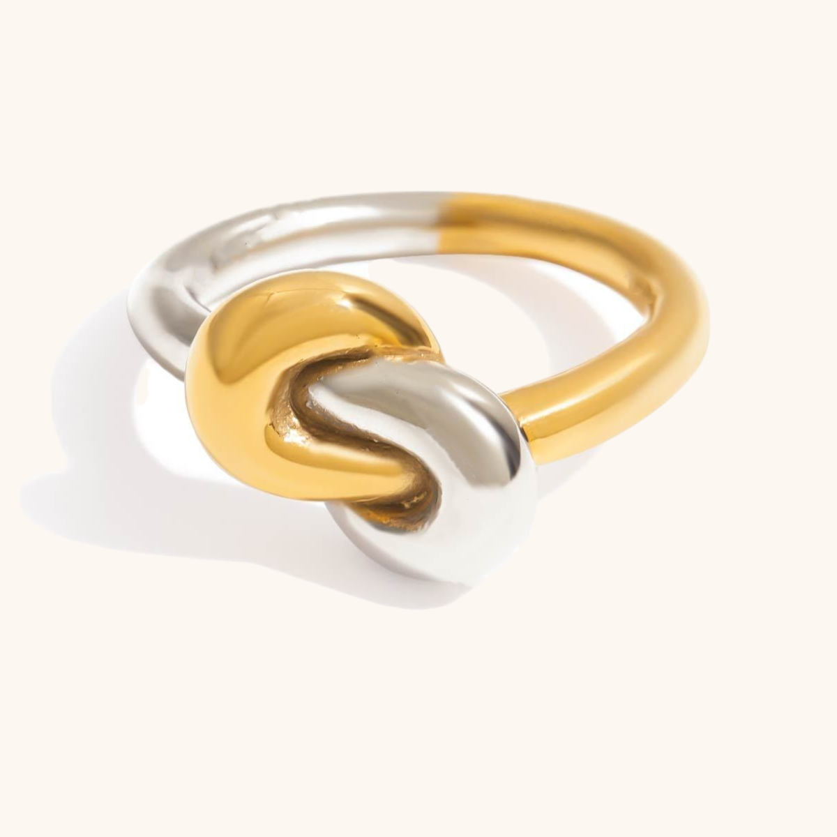 Gold and silver knot ring styled on hand with layered jewelry
