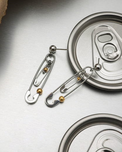 Silver and gold safety pin earrings paired with soda can lid for grunge aesthetic
